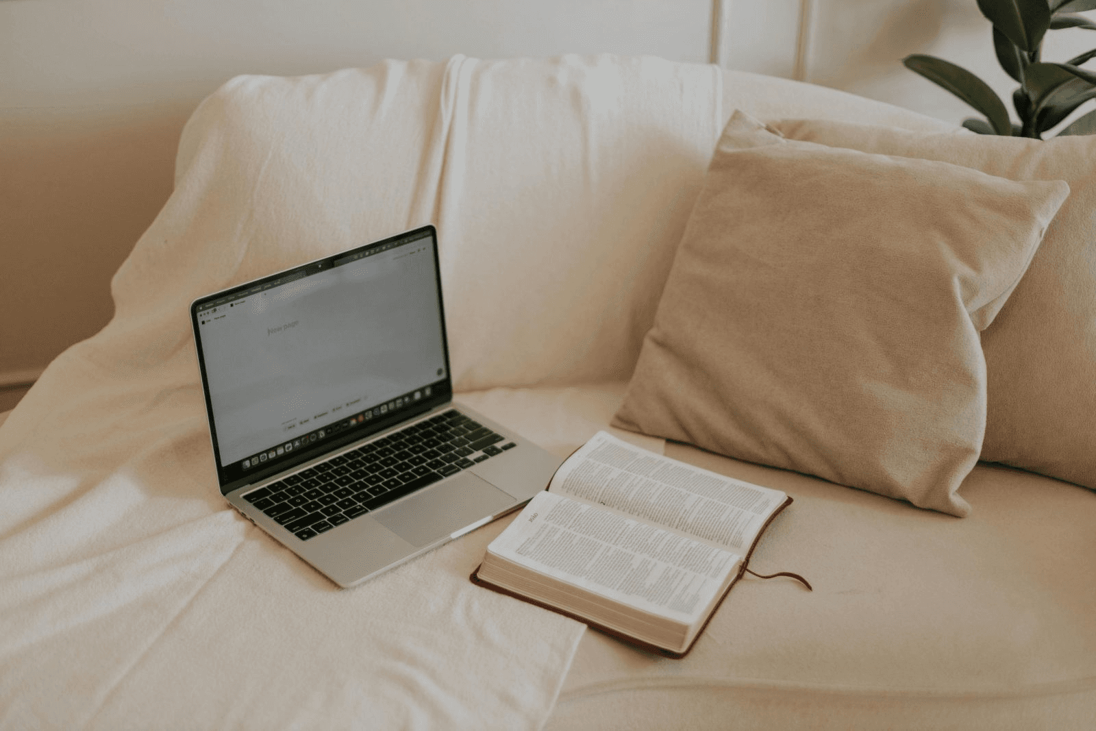 Bíblia e notebook sobre um sofá